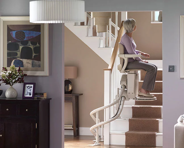 which-stairlift-guide -stairlift reviews-and advice - a- woman-on- a-curved-stairlift- stairlift -part-way-up-the-stairs